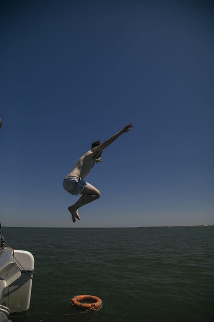 Lisbon: Catamaran Boat Party with Music, Open Bar & Dives - Passing Belém Tower from the river