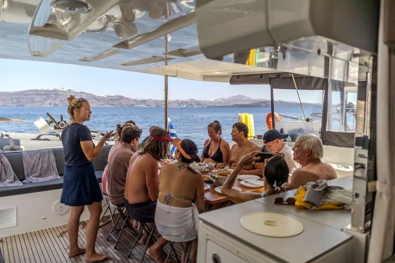 Santorini: Catamaran Cruise with Fresh Meal & Open Bar - Akrotiri Lighthouse beneath the caldera cliffs