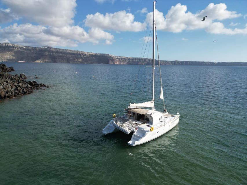 Santorini: Catamaran Cruise with Greek BBQ and Drinks - Red Beach, where the cliffs set the tone