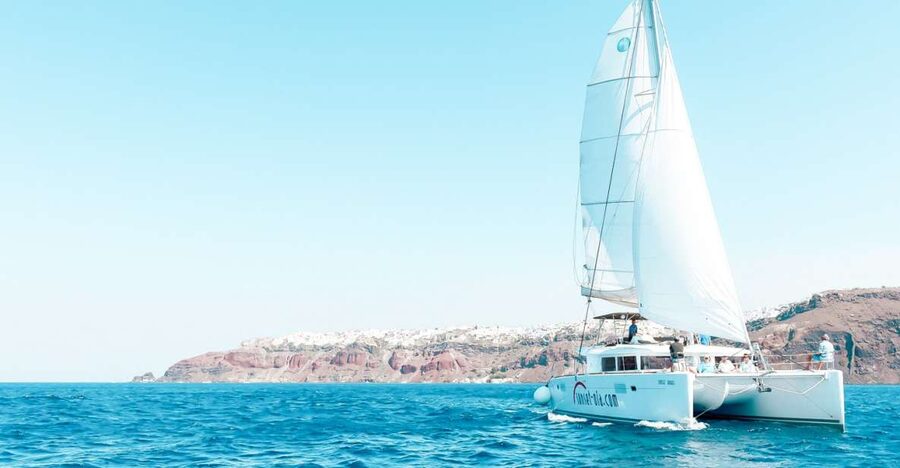 Santorini: Catamaran Tour with BBQ Meal and Unlimited Drinks - A sea-level view of Santorini